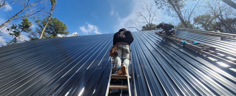 New black metal roof with a worker on a ladder