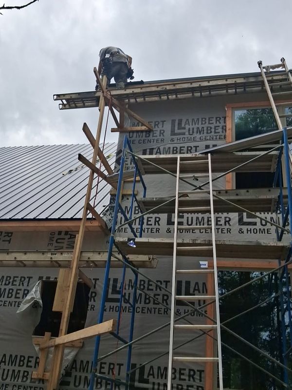 Worker on scaffolding finishing the edge of a metal roof