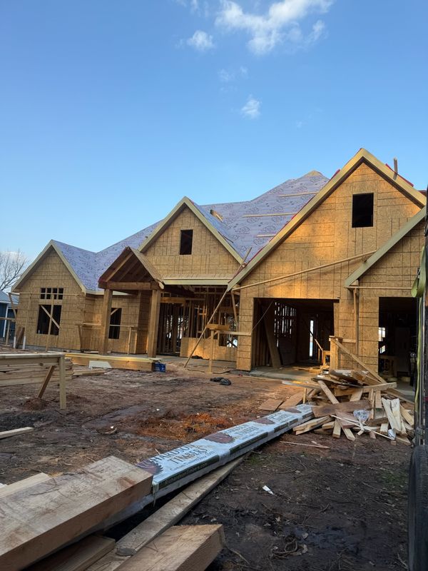 Large new construction house with the roof decked and covered in synthetic underlayment
